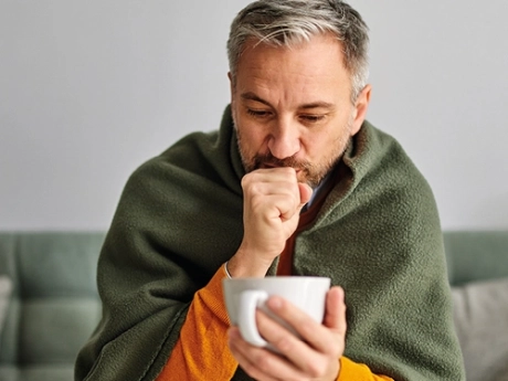 Coughing man holding a cup 