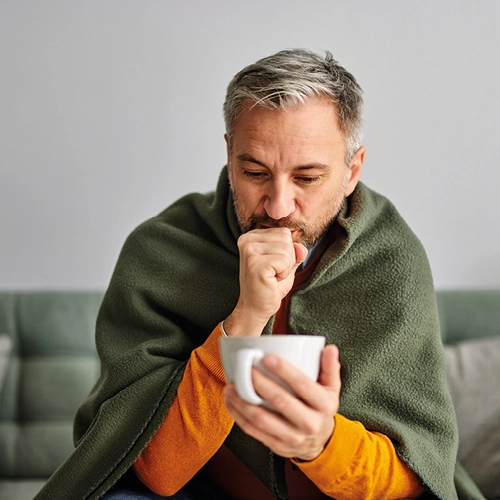 Coughing man holding a cup 
